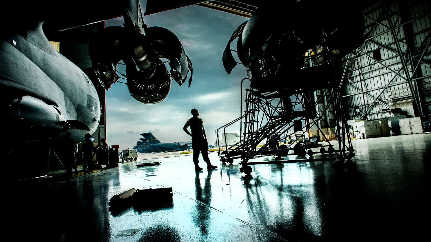 silhouette of an airman in hangar looking at an aircraft